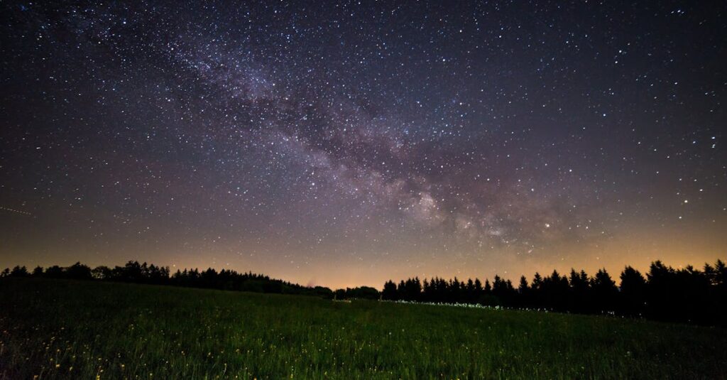 A breathtaking view of a starry night sky over a quiet field, showcasing the Milky Way.