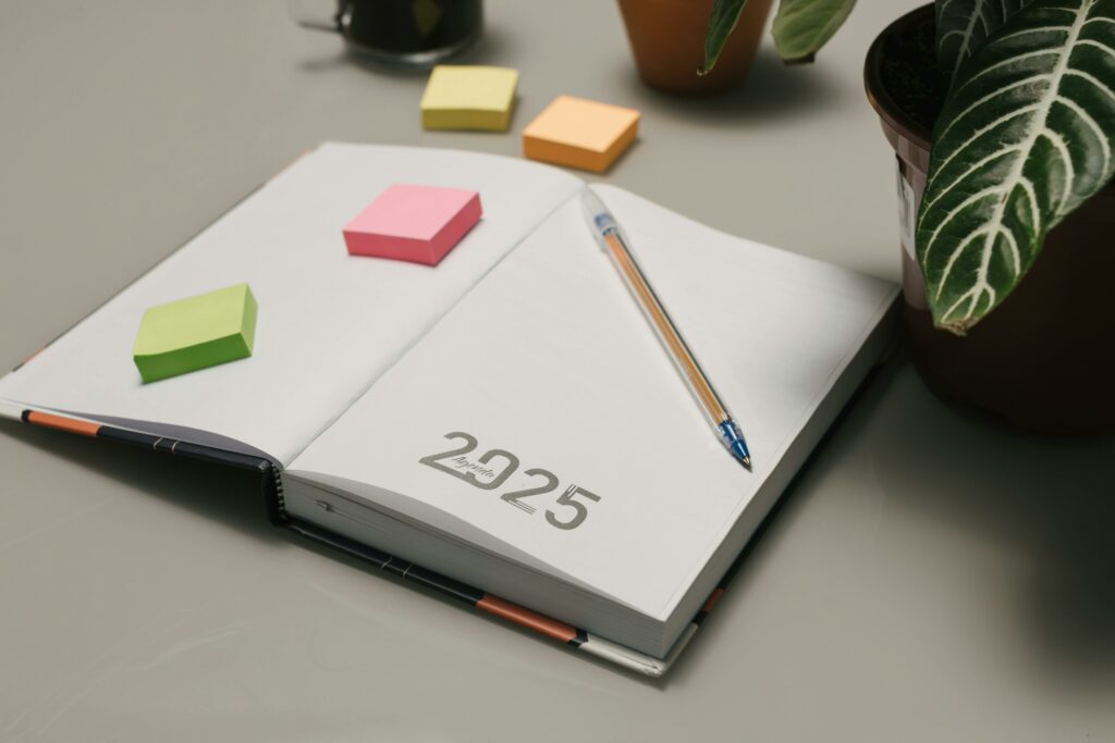 Calendrier 2025 avec des post-it colorés et un crayon, illustrant la planification et l'organisation pour l'année à venir.
