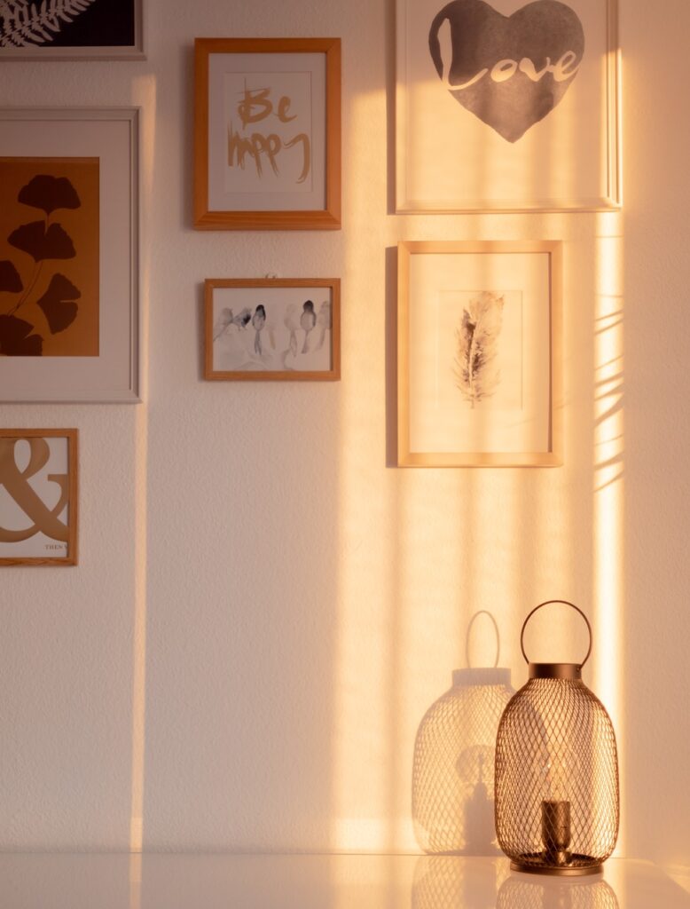 Une lumière douce pour alléger l'esprit Mur décoré de cadres aux illustrations douces, baigné par une lumière dorée en fin de journée, créant une ambiance chaleureuse et apaisante.