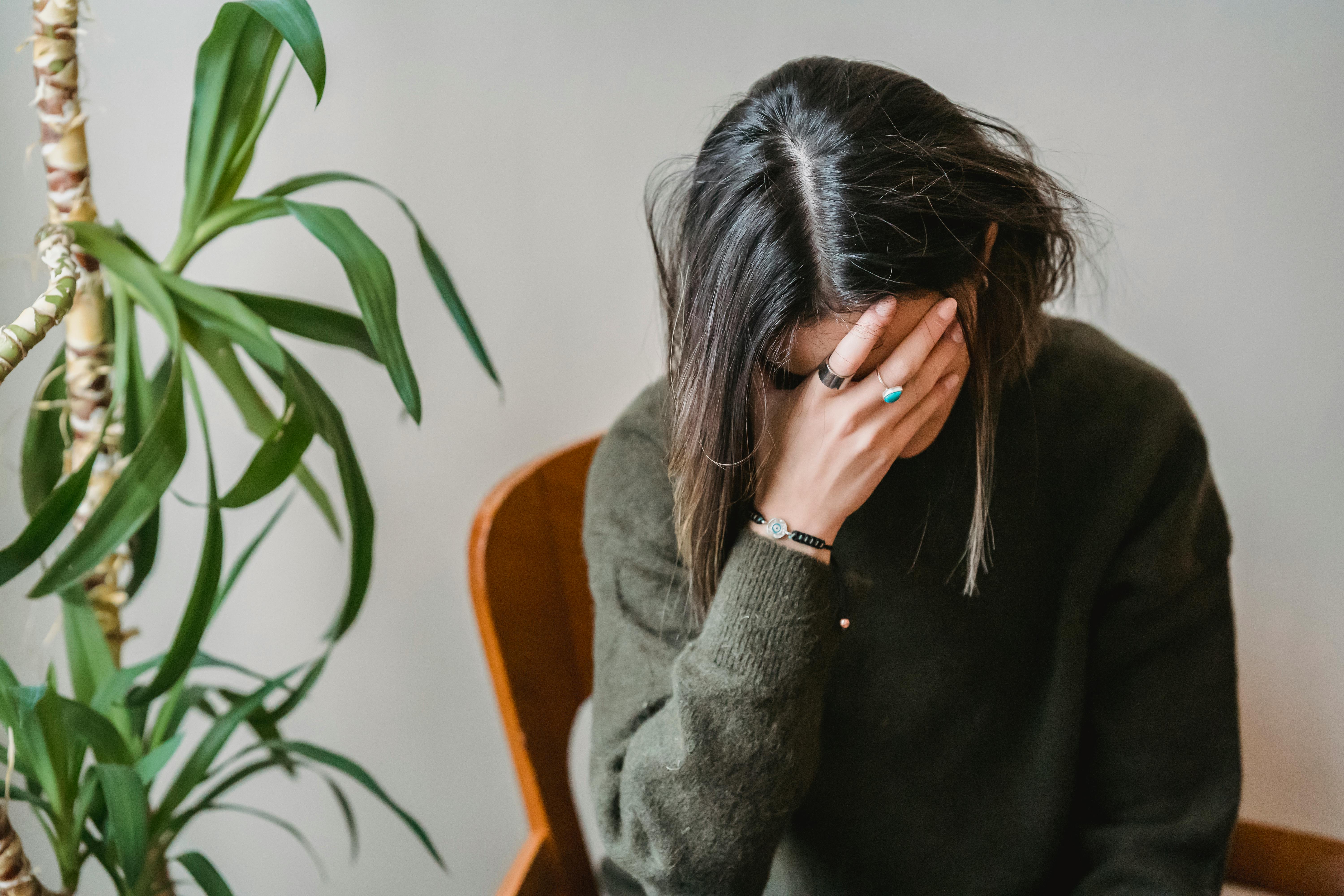 Femme assise, la tête dans la main, symbolisant la charge mentale et l'épuisement