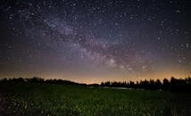 A breathtaking view of a starry night sky over a quiet field, showcasing the Milky Way.